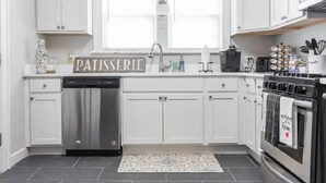 Eine moderne Küche mit weißen Schränken, einem Edelstahl-Geschirrspüler und einem Backofen, an dem ein Handtuch hängt.