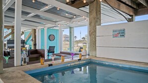 Un área de piscina interior con dardos, barra y un cartel en la pared.