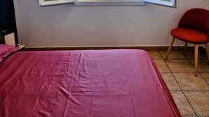 A room with a bed, a red chair, and a window with an open view of the sea. - Large T3 • Breathtaking ocean view - Saint-Gilles (Saint-Paul)