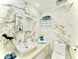 A bathroom with a marble sink, a mirror, a towel rack, and a toilet. - La Mirada Deluxe Suites with Oceanview (Lapu-Lapu)