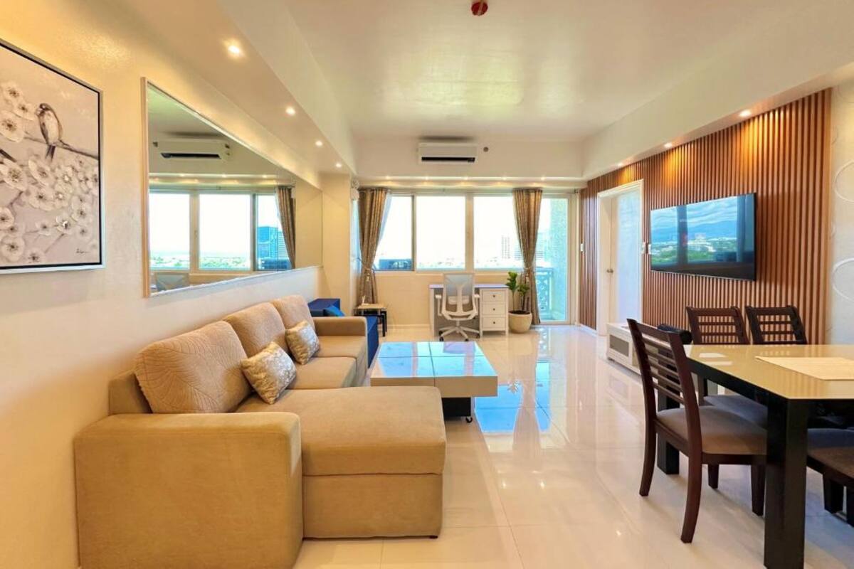 A modern living room with a sofa, a dining table, and a TV.