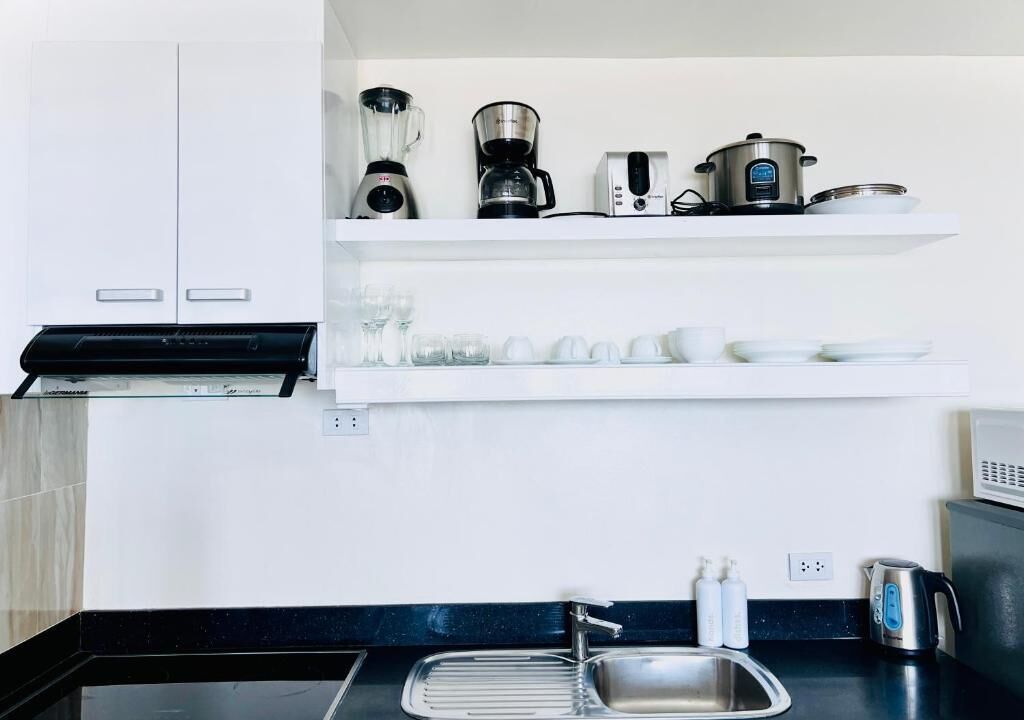 A modern kitchen with a black countertop, stainless steel sink, and white cabinets.