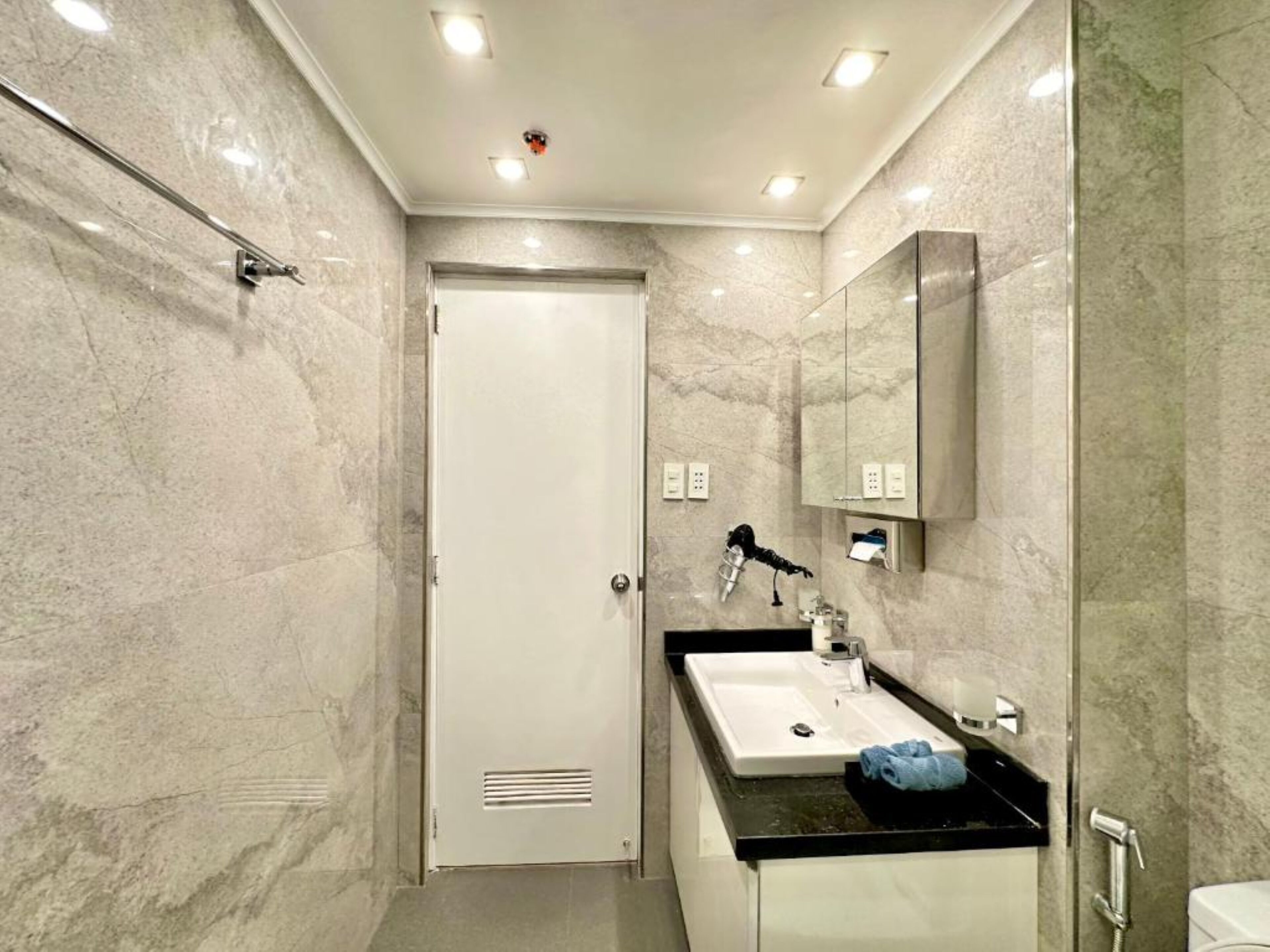 Een moderne badkamer met een witte deur, een wastafel met spiegel en een douchehoek.
