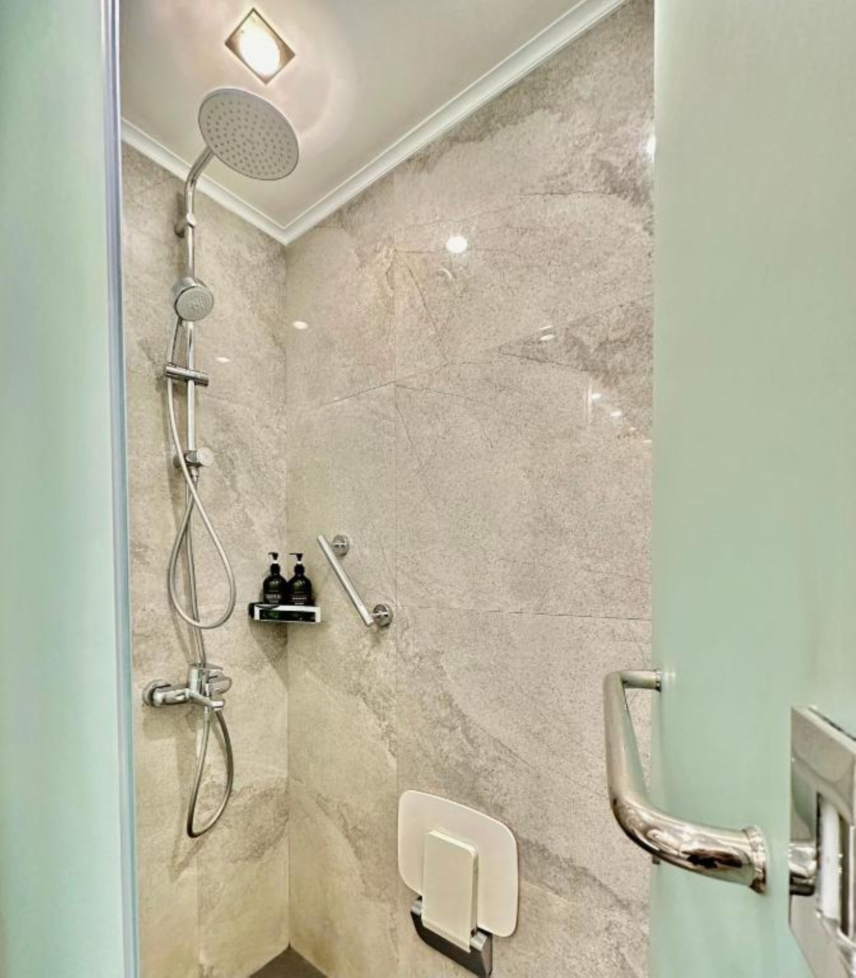 Une salle de bain moderne équipée d’une douche, d’un sèche-mains et d’un distributeur de serviettes.