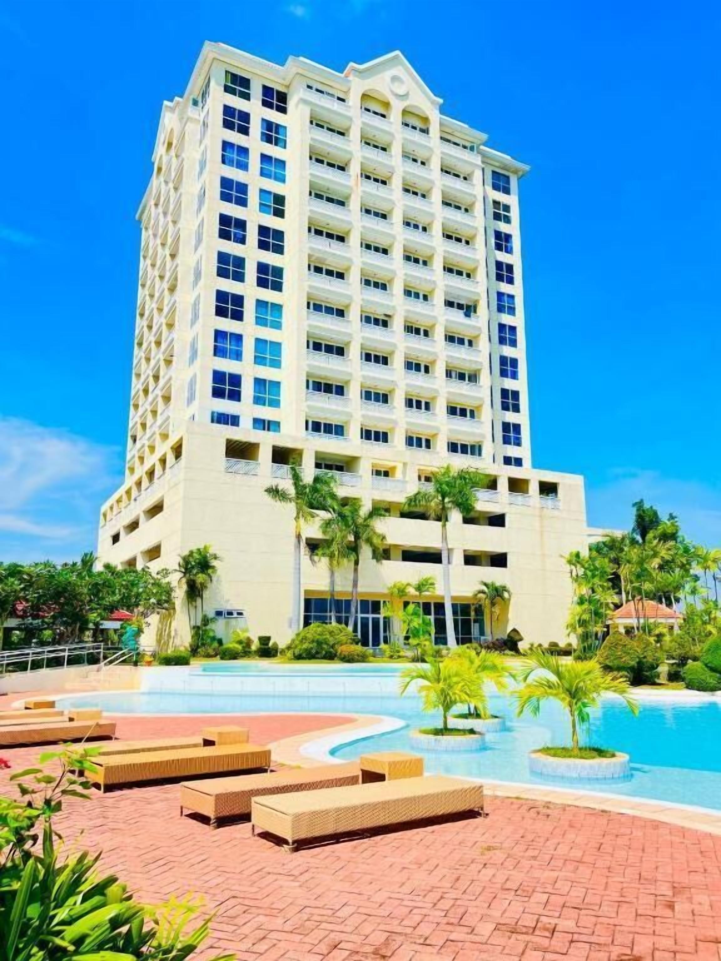 Un hôtel à plusieurs étages doté d’un espace piscine comprenant des chaises longues et une piscine.