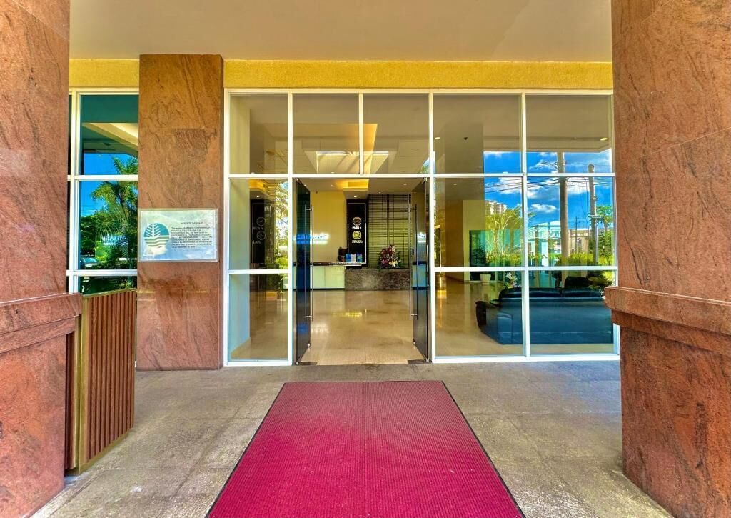 A hotel entrance with a red carpet, glass doors, and a view of the street outside.