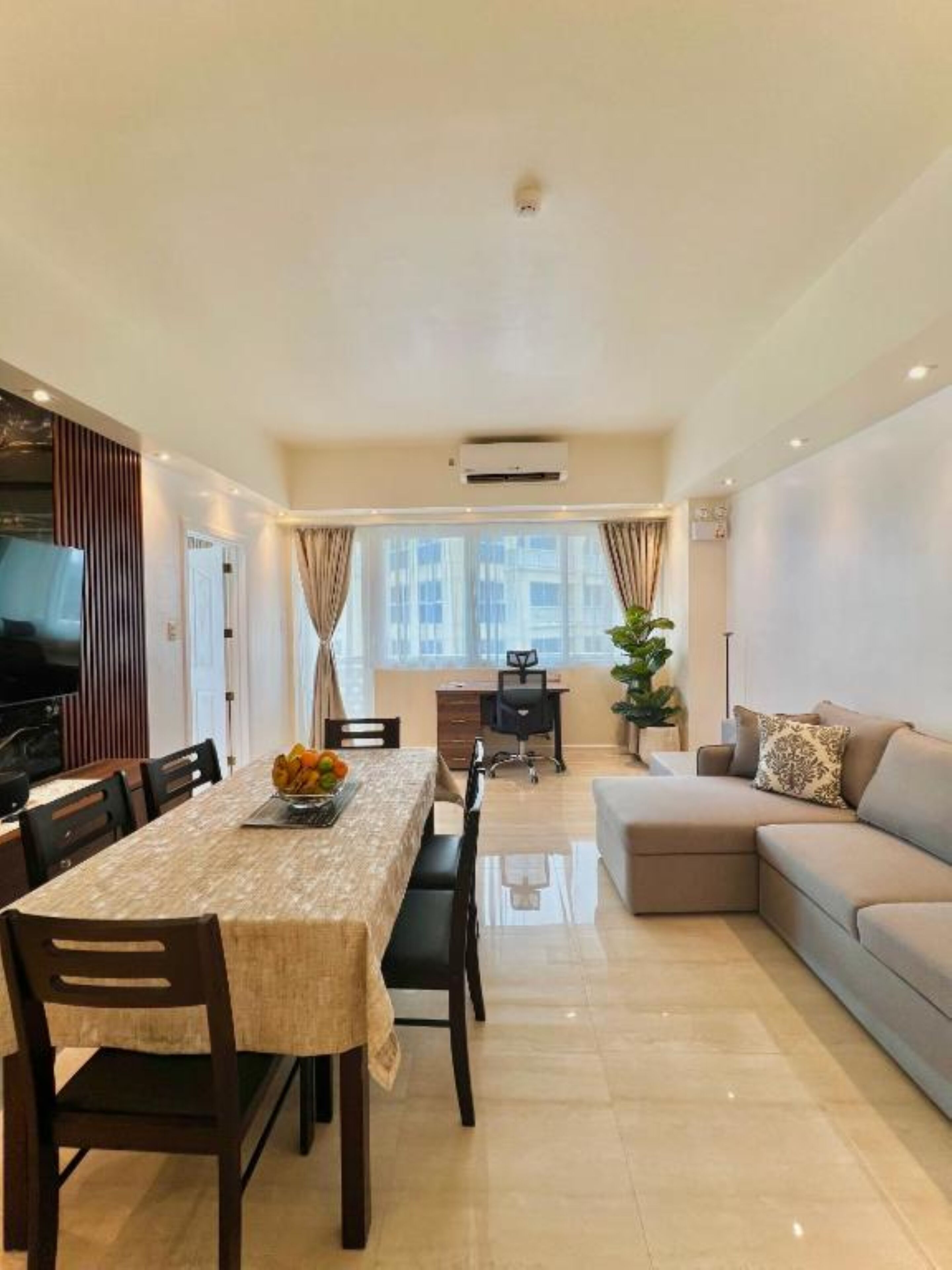 A modern living room with a dining area, a sofa, and a TV.