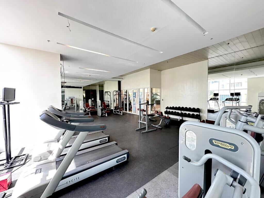 A gym with treadmills, weight machines, and a mirrored wall.