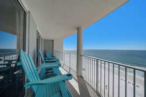 Ein Balkon mit türkisfarbenen Stühlen und Blick aufs Meer.