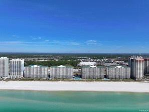 Un paisaje urbano costero con hoteles de gran altura, una playa y un cielo azul despejado.