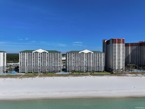 A beachfront hotel with multiple high-rise buildings, a sandy beach, and clear blue skies. - Beachfront Long Beach Tower IV 1205, Pools, Hot Tub, FREE Golf & Perks! (Panama City Beach)