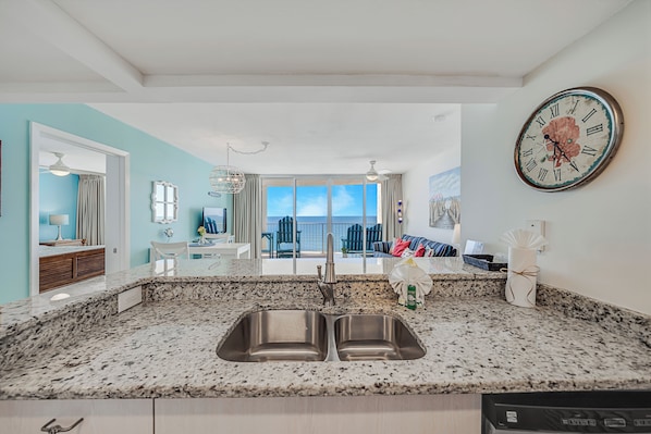 Una cocina con un lavamanos doble, una zona de comedor con vistas y un reloj grande en la pared.