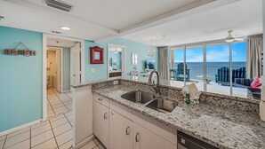 A kitchen with a large window, a sink, and a view of the ocean. - Beachfront Long Beach Tower IV 1205, Pools, Hot Tub, FREE Golf & Perks! (Panama City Beach)