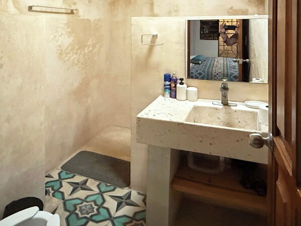 Baño con lavamanos, espejo y baldosas de piso con diseño.