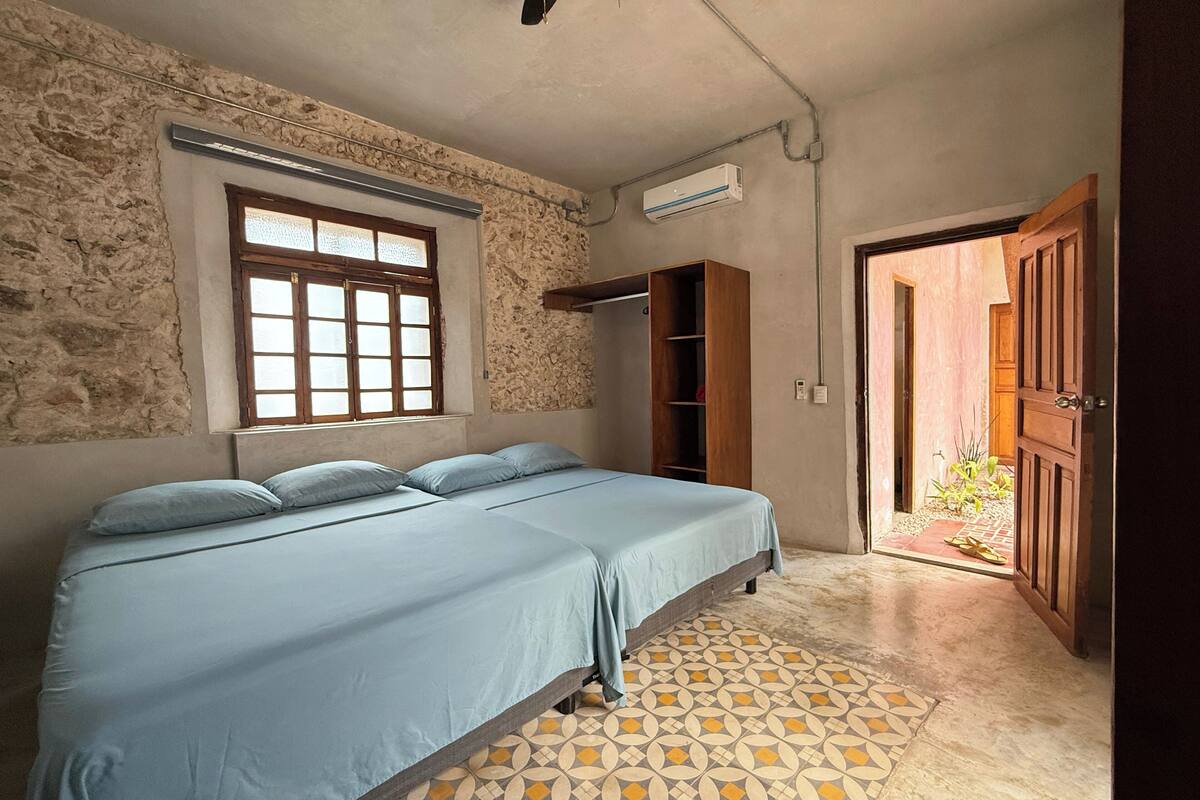 A bedroom with a bed, a window, a wardrobe, and a door leading outside.
