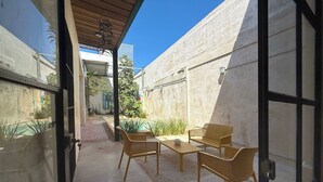 Une terrasse extérieure avec une table et des chaises, une piscine et une vue sur la rue.