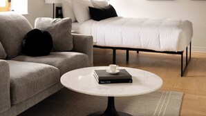 A modern living room with a sofa, a coffee table, a bed, and abstract wall art.