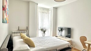 A modern hotel room with a bed, a desk, a chair, a television, and a window with curtains. - Vivodomo | Free parking, top location, modern (Madrid)