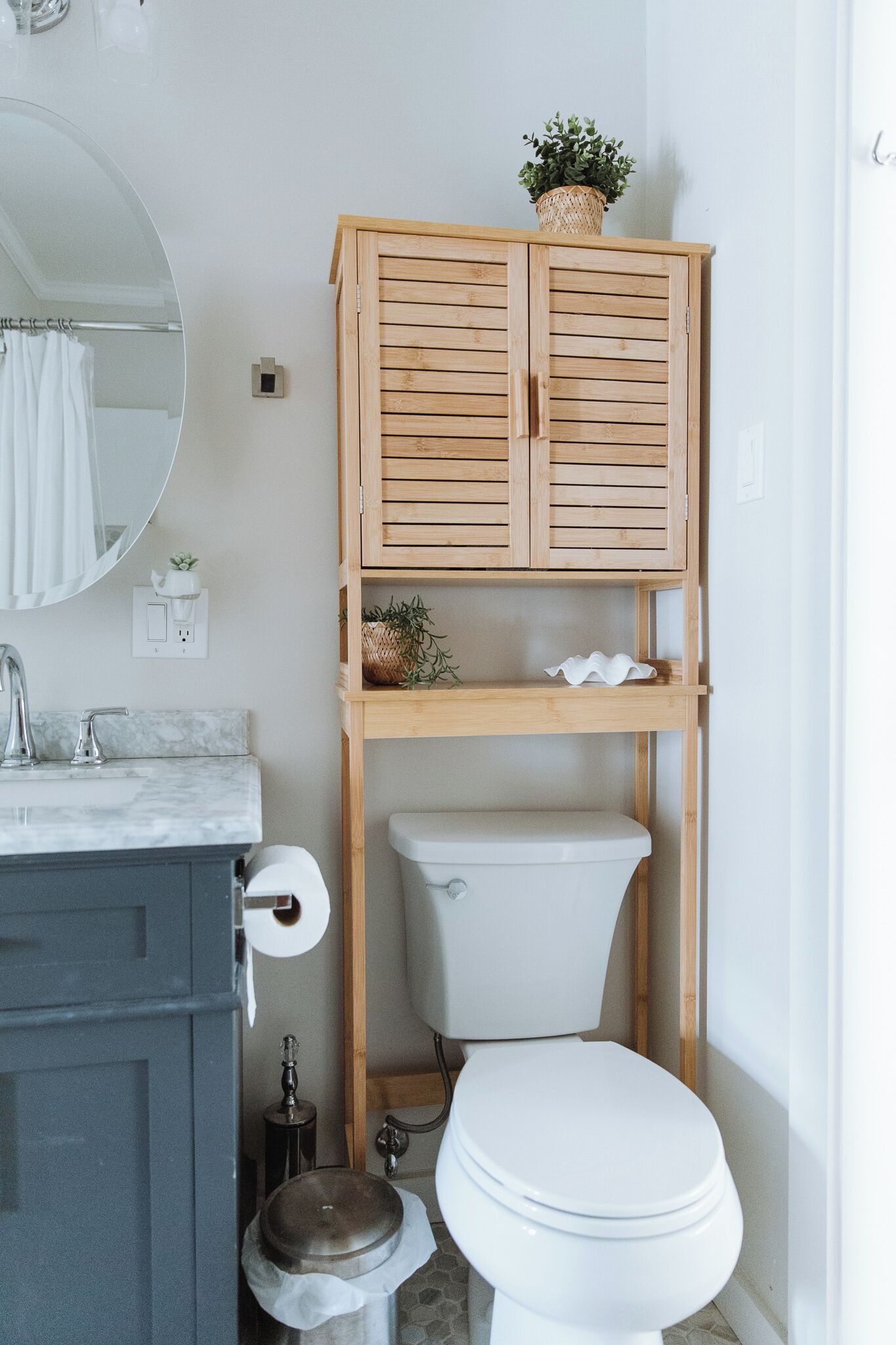 A bathroom with a wooden cabinet, a toilet, a sink, and a mirror.