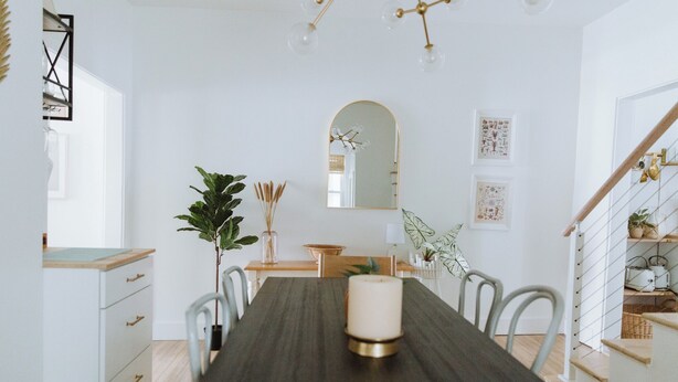 A dining area with a long table, chairs, a candle centerpiece, and a staircase with a railing. - Walk to Dining, Beach & Park~Family Friendly Home! (Cape Charles)