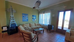 Una sala de estar con un sofá, sillones, una mesa de centro, un televisor y una maqueta de un puente.