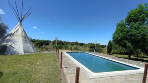 Una piscina con borde de hormigón y zona ajardinada.