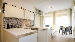 Moderni keittiö, jossa on astianpesukone, kahvinkeitin ja laatoitettu välitila.