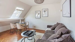 Un salon moderne comprenant un coin repas, un ensemble de canapés et deux œuvres d’art encadrées accrochées au mur.