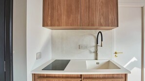 Une cuisine avec des meubles en bois, un plan de travail noir, un robinet en acier inoxydable et un évier à deux bacs.