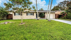 A single-story house with a well-maintained lawn and a small tree in the front yard. - Fort Lauderdale Oasis: 4BR, Pool & Game Room (Fort Lauderdale)