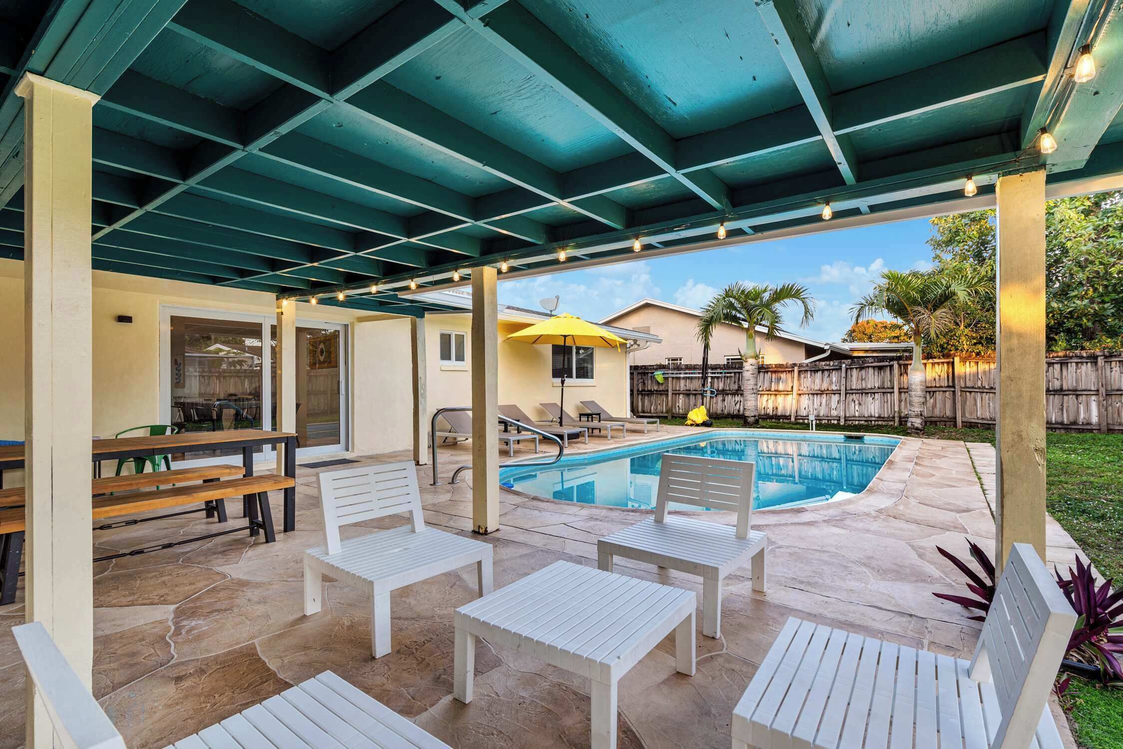 A covered outdoor area with a pool, seating, and a patio.