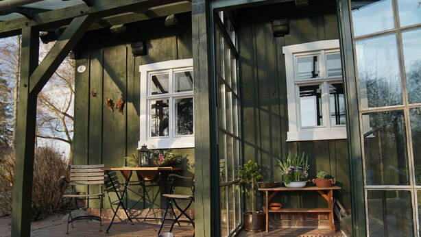 Una estructura de madera con dos ventanas, una mesa y sillas afuera.