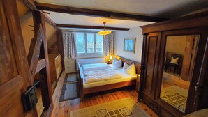 Un dormitorio acogedor con una cama de madera, una mesita de noche con lámpara y una ventana con cortinas.