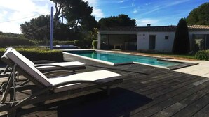 Een houten terras met ligstoelen en een zwembad.