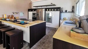 Een moderne keuken met een centraal eiland, inbouwapparatuur en barstoelen.