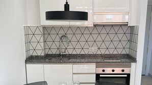 Una cocina moderna con armarios blancos, una encimera negra y un horno empotrado.