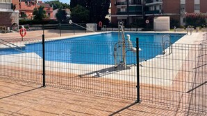 Una piscina con cerco de seguridad, rodeada por un patio de ladrillo.