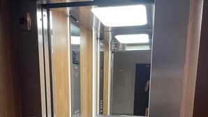 An elevator with a digital display, a metallic interior, and a wooden panel on the wall.
