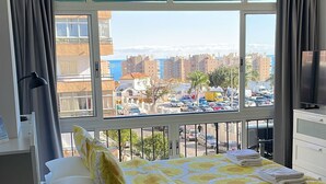 Una habitación de hotel con cama, sofá, televisión y balcón con vistas a la ciudad.