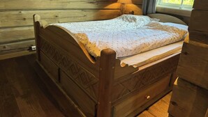 Una cama de madera con un edredón estampado con estrellas en una habitación de estilo cabaña, con ventana y lámpara.