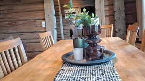 Una mesa de madera para comer con un posavasos tejido, rodeada de sillas.
