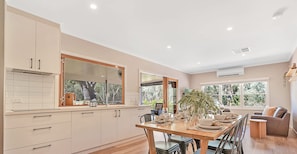 A modern kitchen with a dining area, large windows, and a view of the outdoors. - The Rad Shack - Echuca Holiday Homes (Echuca)