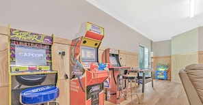 A room with arcade games like Street Fighter, Capcom, and NBA Jam. There is a couch and a small table with a toy. - The Rad Shack - Echuca Holiday Homes (Echuca)