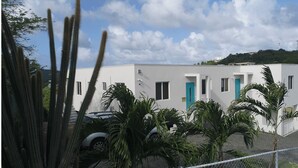 A modern building with a white exterior, a blue door, and a car parked in front. - Hilltop Condos Unit 3 - 1-bedroom with AC, WiFi centrally located in Gros Islet (Gros Islet)