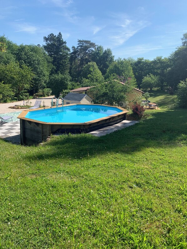 A rectangular swimming pool with a wooden deck surrounding it, set in a grassy area with trees in the background. - Gîte l'Arbre de Vie 24 in a haven of peace in the heart of Périgord Noir (Nabirat)