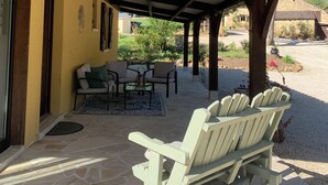 Ein überdachter Patio-Bereich mit Steinböden, Holzmöbeln und Blick auf die umliegende Landschaft.
