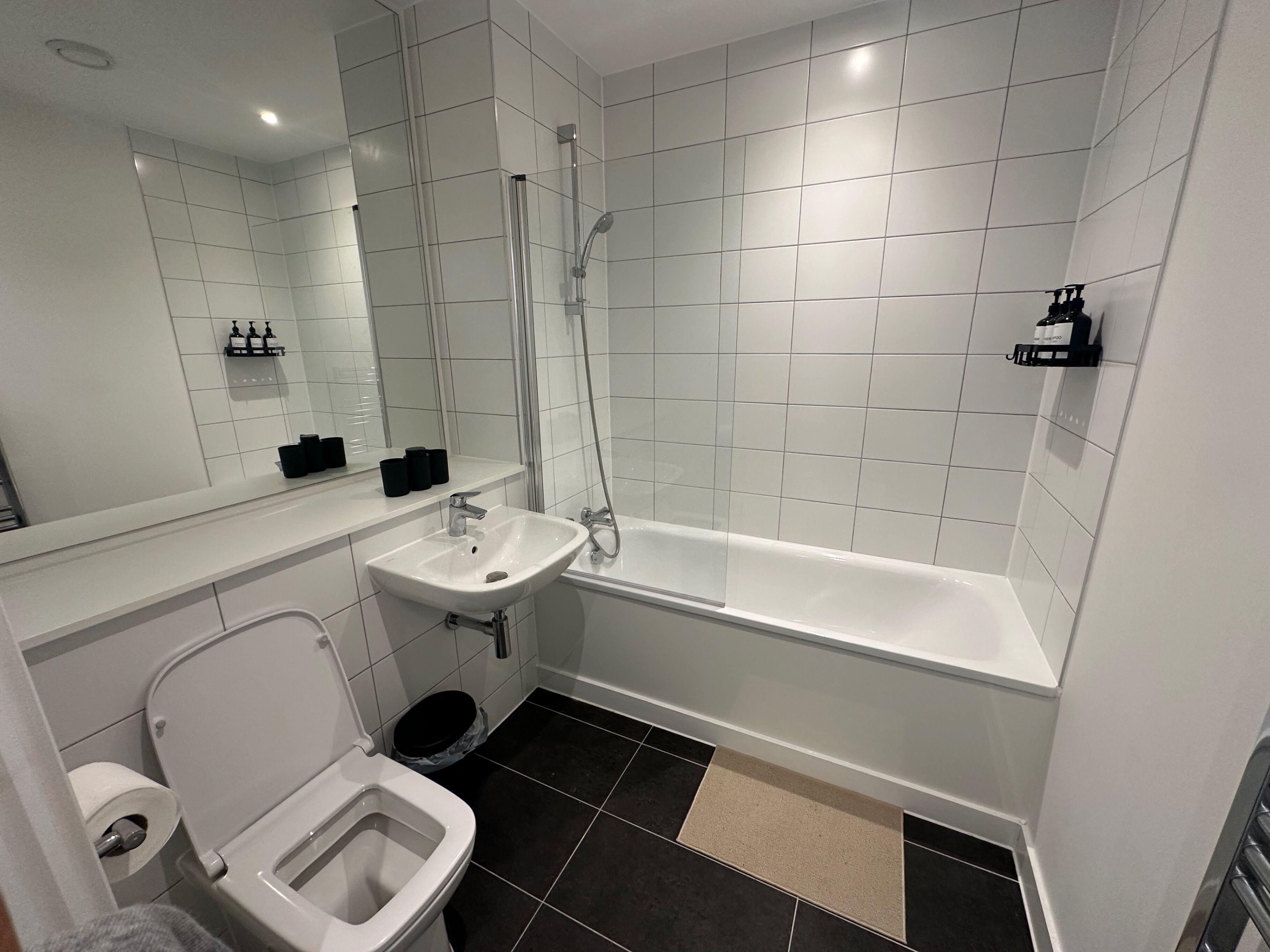 A modern bathroom with a toilet, sink, and bathtub.