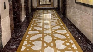 A hallway with marble floors and walls, leading to a room with a decorative ceiling and a sign with Arabic script. - RAFAHEYAT Hotel (Makkah)