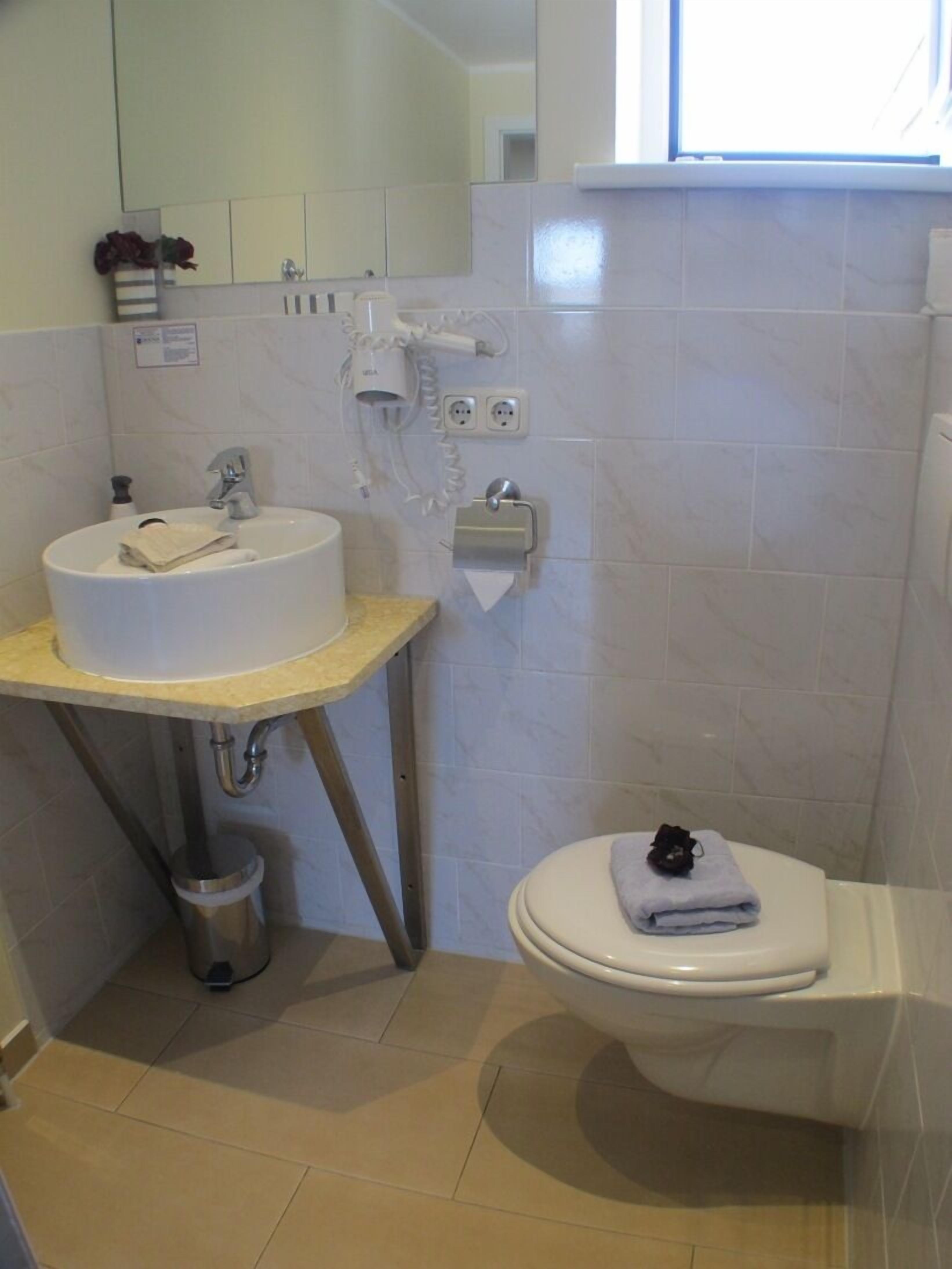 Un baño con lavamanos, inodoro y perchero para toallas.