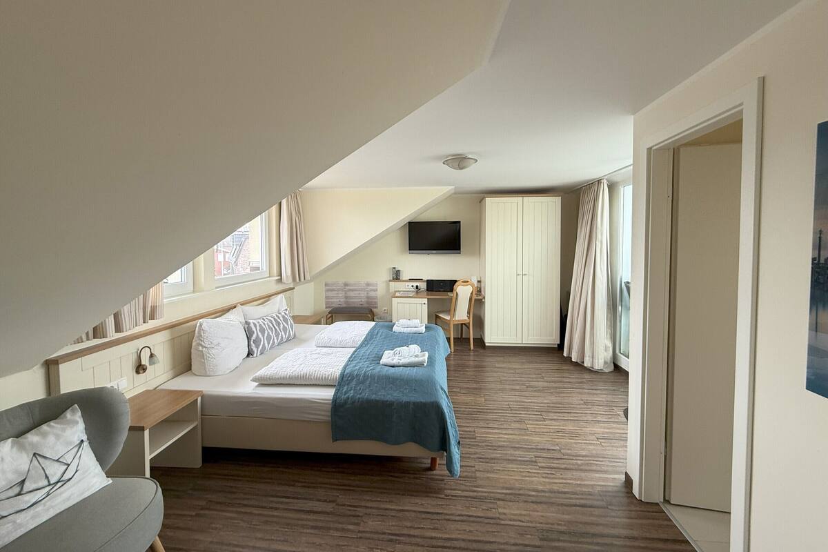Ein Schlafzimmer mit einem Bett, einem Schreibtisch, einem Stuhl und einem Kleiderschrank.